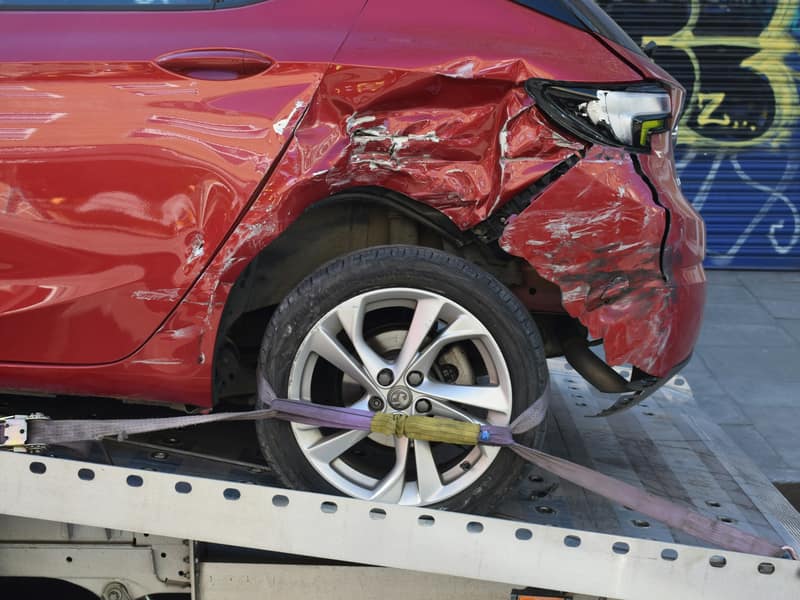 Coche rojo con golpe lateral cargado sobre una grúa